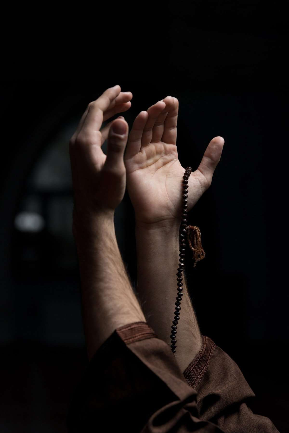 uplifted hands with rosary beads