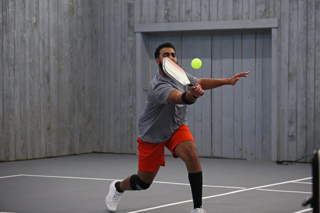 Man playing pickleball returns a serve during off campus activities for addiction recovery, 
