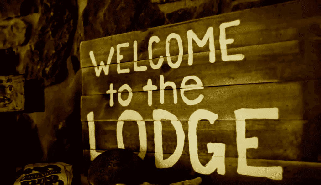 wooden sign with white lettering reads "welcome to the lodge"