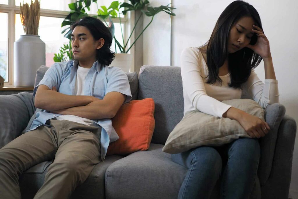 Disconnected couple with folded arms avoiding eye contact with each other.