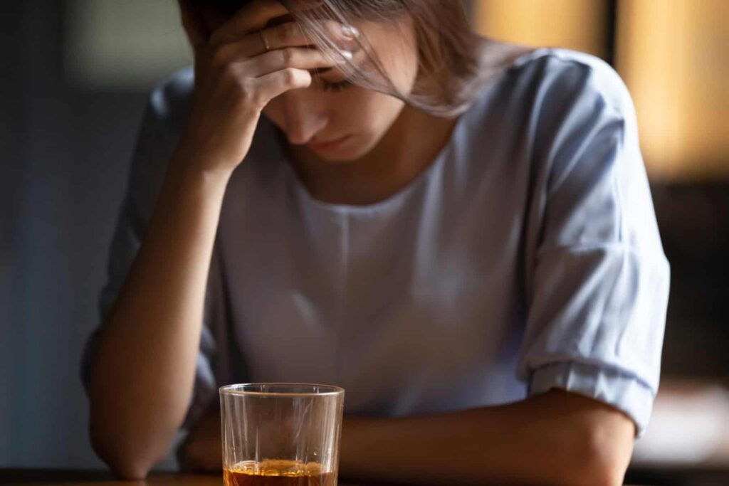 women with head in hand drinking